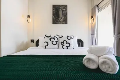 a bedroom with a bed with white sheets and a green rug at Wink City 1 Patong Beach 4bedrooms in Patong Beach