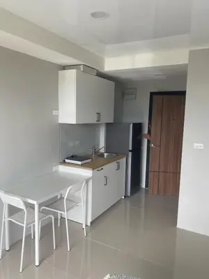 a kitchen with a table and chairs and a refrigerator at май кхао Студия в кондо 777 in Koh Lone
