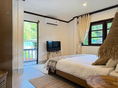 a bedroom with a bed and a tv and a window at Jungle style villa 3br in Kamala Beach