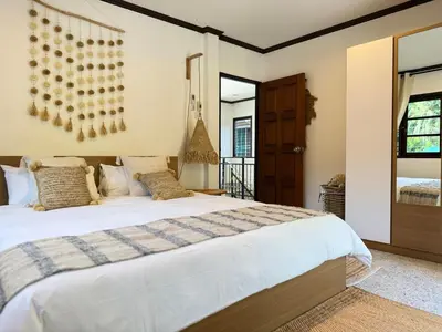 a bedroom with a large bed with white sheets at Jungle style villa 3br in Kamala Beach