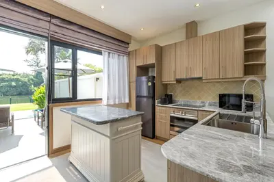 a kitchen with wooden cabinets and a large window at Golden Cotton Villa 3BR Lagoon View by GRF in Laguna Phuket