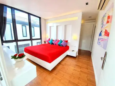 a bedroom with a large bed with red sheets and blue pillows at Beautiful Modern Penthouse Kamala Beach in Kamala Beach