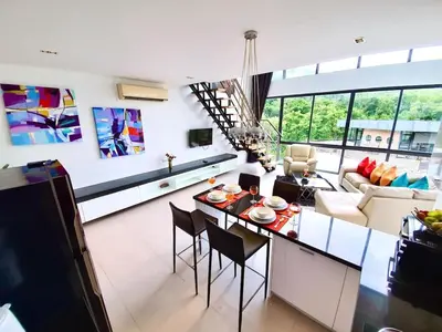 a kitchen and living room with a table and chairs at Beautiful Modern Penthouse Kamala Beach in Kamala Beach