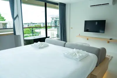a bedroom with a white bed and a large window at Utopia Karon in Kata Beach