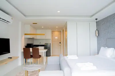 a white bedroom with a white couch and a kitchen at Utopia Karon in Kata Beach