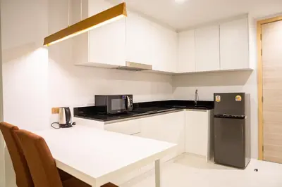 a kitchen with white cabinets and a black refrigerator at Utopia Karon in Kata Beach