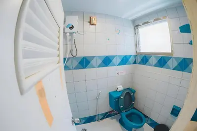 a bathroom with a blue toilet and a window at xx Mitr INN Phuket Oldtown - มิตร ภูเก็ต in Phuket Town