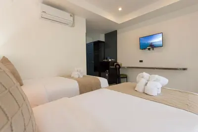 a hotel room with two beds and a tv at XL PATONG Hotel in Patong Beach