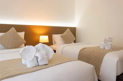 a hotel room with three beds with towels on them at XL PATONG Hotel in Patong Beach