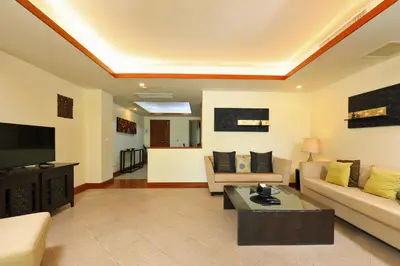 a living room with a couch and a tv at Tropical Holiday Home at Laguna Phuket in Layan Beach