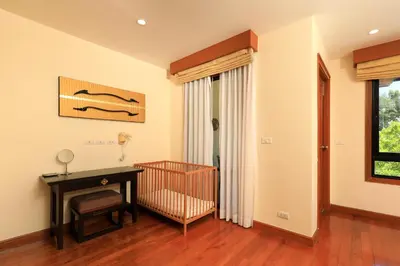 a baby room with a crib and a table at Tropical Holiday Home at Laguna Phuket in Layan Beach