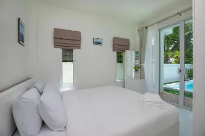 a white bedroom with a large bed with white pillows at The White House Kamala Beachfront in Kamala Beach