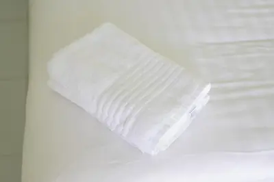 a roll of white toilet paper sitting on a bed at The White House Kamala Beachfront in Kamala Beach