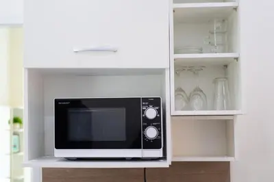a microwave on a shelf in a kitchen at The White House Kamala Beachfront in Kamala Beach