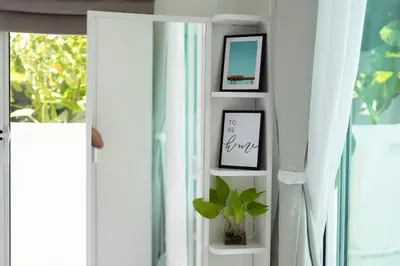 a shelf with two pictures and a plant next to a window at The White House Kamala Beachfront in Kamala Beach