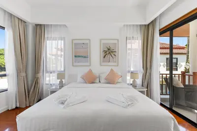 a bedroom with a large white bed with windows at Coastal Villa on Fairway in Phuket