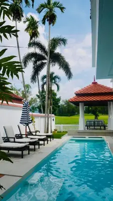 a swimming pool with lounge chairs and palm trees at Coastal Villa on Fairway in Phuket