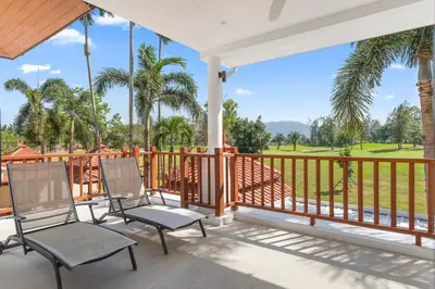 two chairs on a porch with a view of a golf course at Coastal Villa on Fairway in Phuket