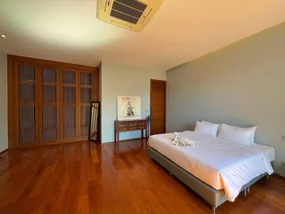 a bedroom with a large bed and a wooden floor at Villa Sa in Ban Saiyuan (1)