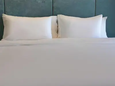 a bed with white sheets and pillows at Laya Suites and Residences in Bang Tao Beach