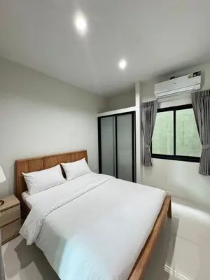 a bedroom with a large white bed and a window at Lela Home in Phuket Town