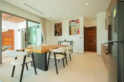 a kitchen and dining room with a wooden table and chairs at 2BR Pool Villa at Shambhala in Laguna Bangtao in Bang Tao Beach
