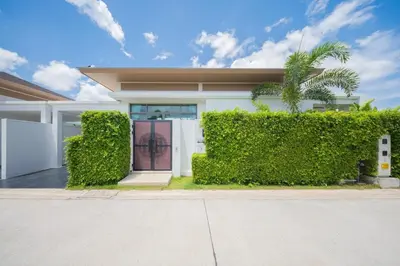 a white house with a green hedge at 2BR Pool Villa at Shambhala in Laguna Bangtao in Bang Tao Beach