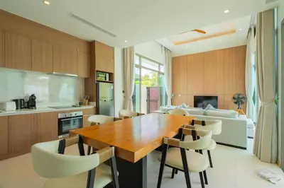 a kitchen and dining room with a wooden table and chairs at 2BR Pool Villa at Shambhala in Laguna Bangtao in Bang Tao Beach