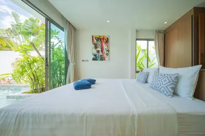a bedroom with a large white bed with a large window at 2BR Pool Villa at Shambhala in Laguna Bangtao in Bang Tao Beach