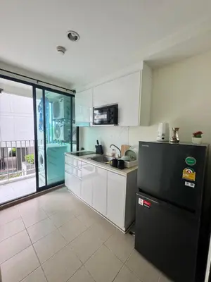 a kitchen with a black refrigerator and a sink at Centrio condo near central Phuket in Ban Rangeng