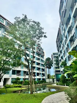 an apartment building with a tree in a park at Centrio condo near central Phuket in Ban Rangeng