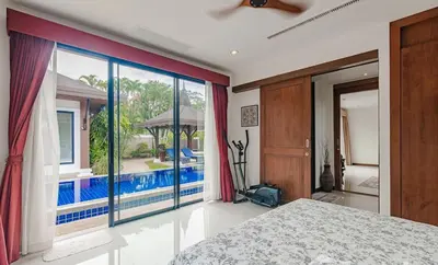 a bedroom with a bed and a view of a pool at 4 BR Jacuzzi Pool Villa with Playground, near Layan, Laguna, Bang Tao beach in Ban Pak Lak