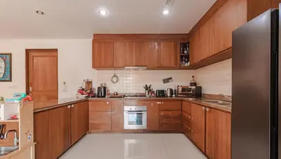a kitchen with wooden cabinets and a stainless steel refrigerator at 4 BR Jacuzzi Pool Villa with Playground, near Layan, Laguna, Bang Tao beach in Ban Pak Lak