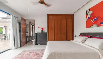 a bedroom with a white bed and a wooden door at 4 BR Jacuzzi Pool Villa with Playground, near Layan, Laguna, Bang Tao beach in Ban Pak Lak