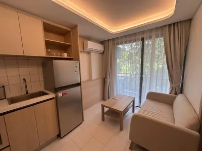 a kitchen with a refrigerator and a table and a couch at Kamala Apartments in Kamala Beach