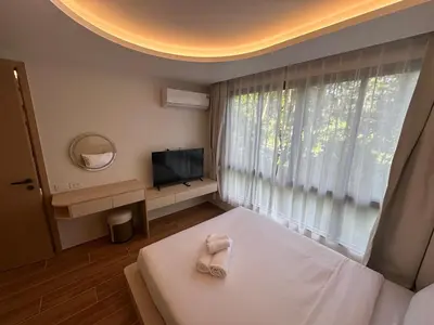 a bedroom with a bed and a tv and a window at Kamala Apartments in Kamala Beach