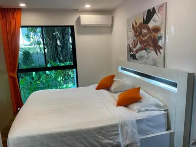 a bedroom with a bed with orange pillows and a window at Rawai Title 3 in Rawai Beach