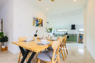 a dining room with a wooden table and chairs at Wink Garden 3 Bedrooms Bangtao Beach Phuket in Ban Thalat Choeng Thale