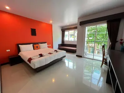 a bedroom with an orange wall and a bed in it at Chollada inn kamala in Kamala Beach
