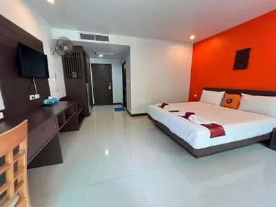 a bedroom with a large bed with an orange wall at Chollada inn kamala in Kamala Beach