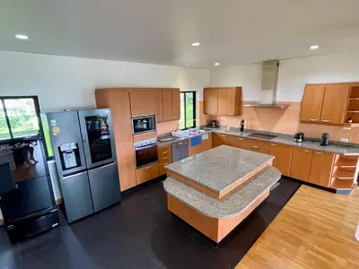 a large kitchen with wooden cabinets and stainless steel appliances at Kata Sunset Bay Villa - 3BR Private Pool - Seaview in Kata Beach