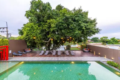 a swimming pool with chairs and a tree at Antiya Hotel Phuket in Phuket Town
