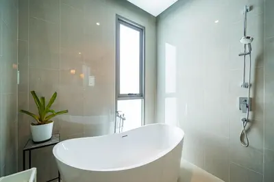 a white bath tub in a bathroom with a window at Teak 5 BR Pool Villa Bang Tao Airport Shuttle in Laguna Phuket