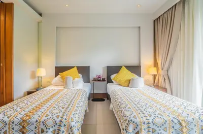 a hotel room with two beds with yellow pillows at Elegant Beachfront 3BR Condo at Pearl of Naithon in Nai Thon Beach