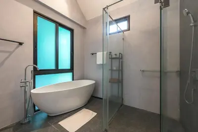 a bathroom with a tub and a glass shower at V188 The Granary Loft Haven 3BR Pool Sanctuary in Bang Tao Beach