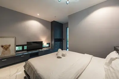 a bedroom with a large white bed and a flat screen tv at V188 The Granary Loft Haven 3BR Pool Sanctuary in Bang Tao Beach