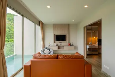 an orange couch in a living room with a large window at Breathtaking Sea & Mountain View Private Pool in Karon Beach