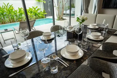 a dining table with glasses and plates on it at Mouana Residence Song Khun Chalong VIP4-bedroom Pool Villa 89-14 in Chalong