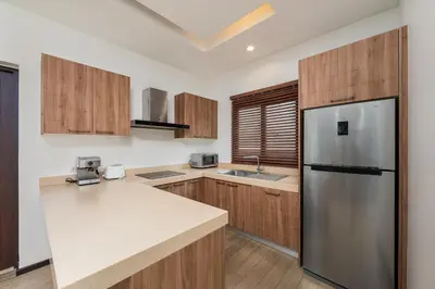 a kitchen with wooden cabinets and a stainless steel refrigerator at Oxygen Villas with Private Pool Near Naiharn by TropicLook in Rawai Beach