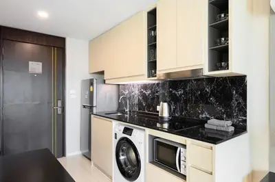a kitchen with a microwave and a washer and dryer at Mida Grande Resort 1106 by Phuket Sabay Rent in Surin Beach